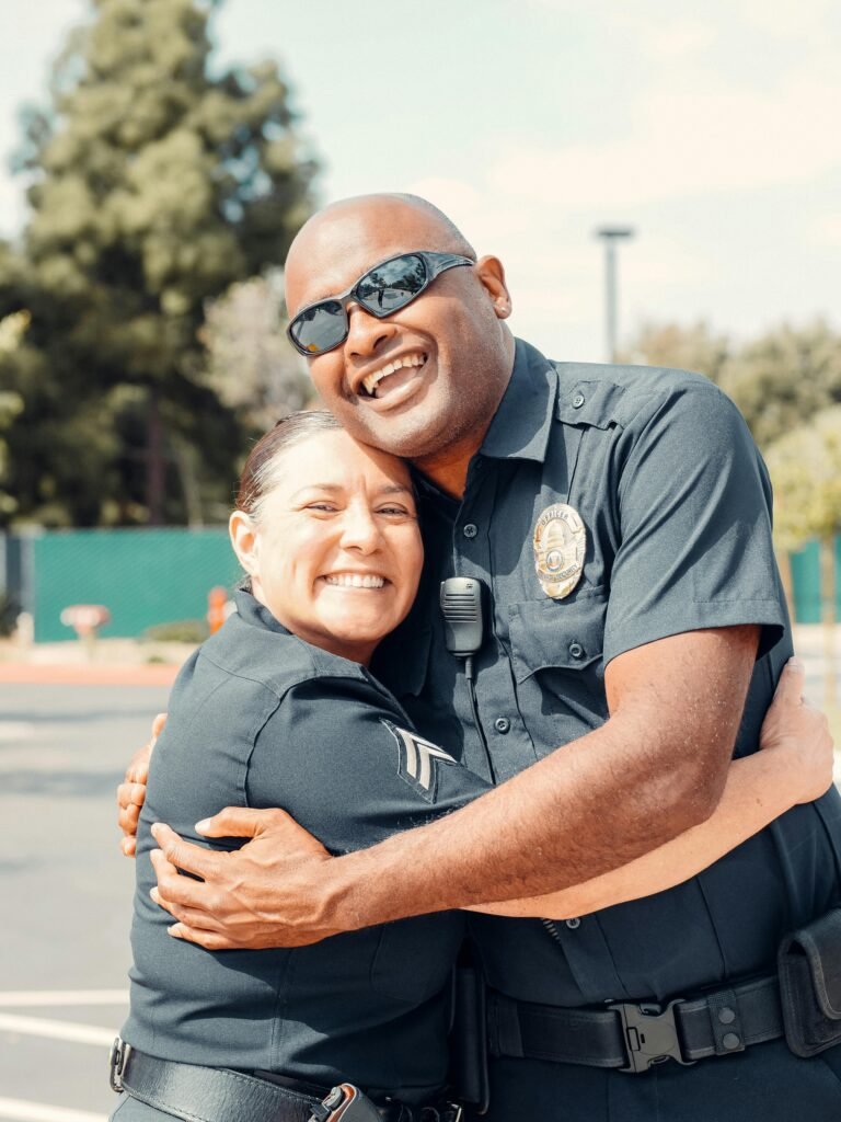 Friendly police officers smiling and hugging outdoors, showcasing community policing.